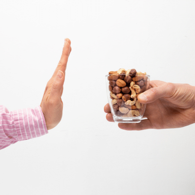 Hand in stop motion to a glass cup of hard nuts, representing foods to avoid with braces