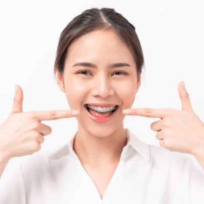 Teenage girl pointing with both hands toward her teeth, representing how orthodontics improves self-esteem