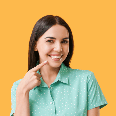 Teenage girl smiling and pointing at her teeth, representing straight teeth and oral health