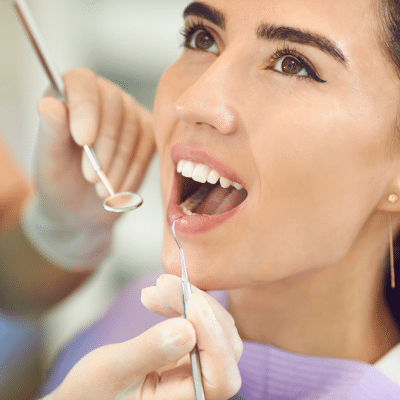 Woman with her mouth wide open while orthodontist works on her teeth, representing first orthodontic appointment
